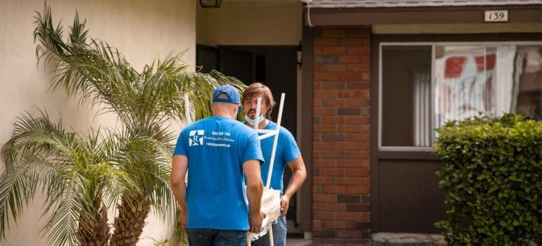 two movers in front of the house carrying tables