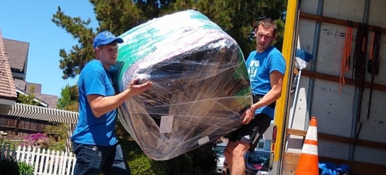 two furniture movers Dallas–Fort Worth metroplex loading a large chair onto a moving truck 