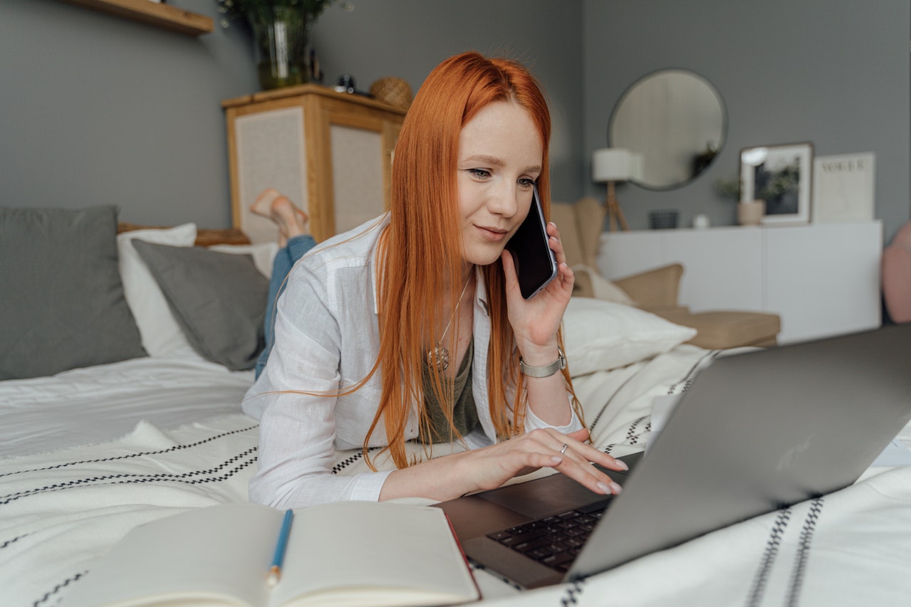 Girl on the bed with a phone and a laptop