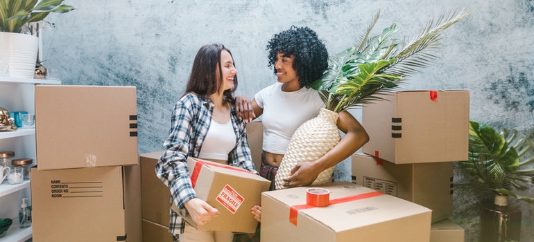 Two women with packed cardboard boxes