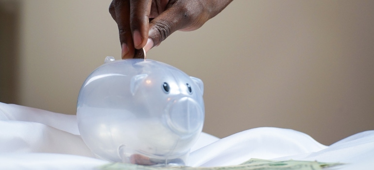 a person putting a coin in a piggy bank after moving from Austin to Phoenix