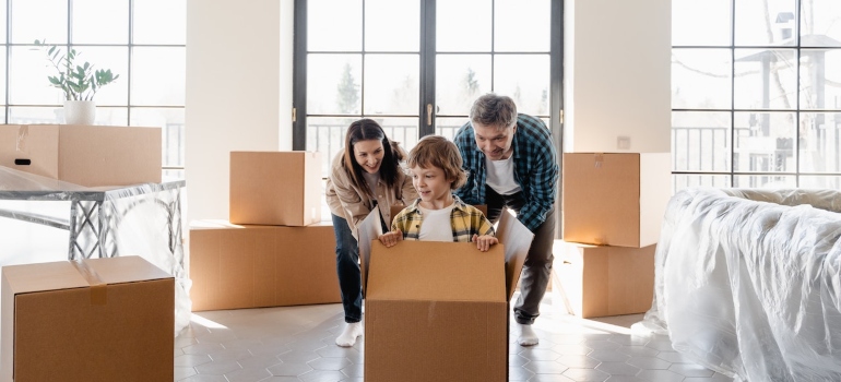 a mother, father and a boy playing with cardboard boxes in their new home