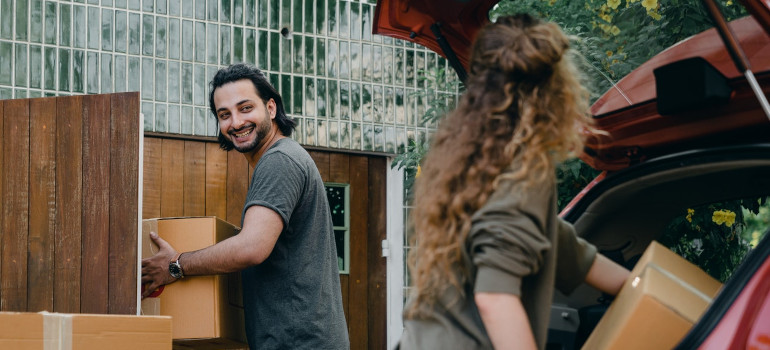 Happy couple unloading automobile while moving 