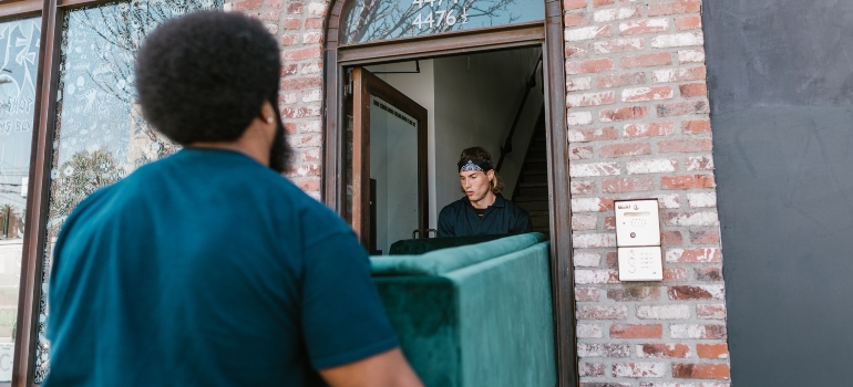 two focused movers TXrrying green sofa