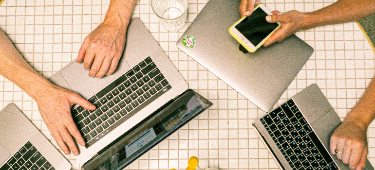 people sitting around a table with laptops and phones