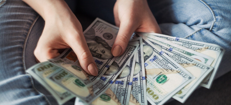 Person holding 100 US dollar banknotes