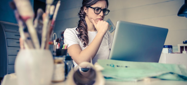 Young woman using a laptop to plan her move and make an office moving checklist