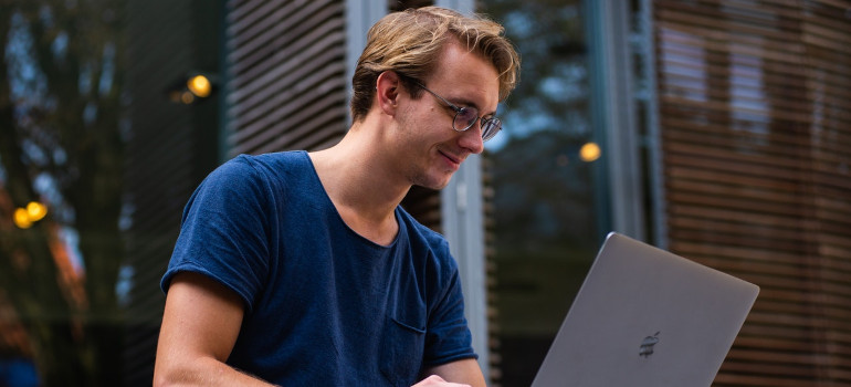 Young man using a laptop to research how much money should he save before moving to LA?