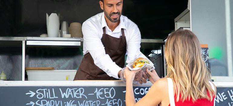 Food trucker giving out a burger to a woman