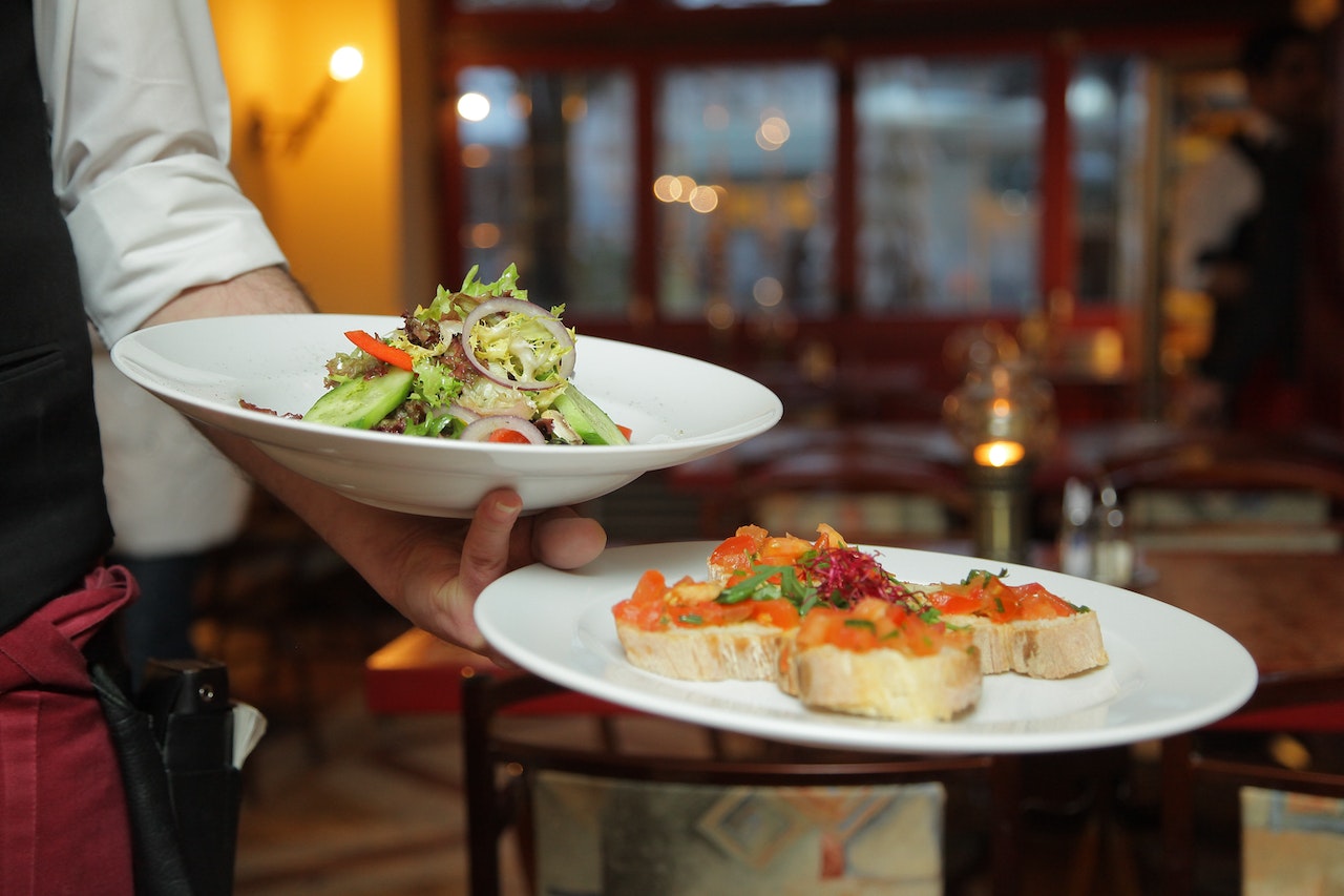 A waiter in a restaurant serving people Exploring the Best LA Eateries