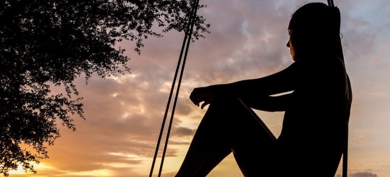 a woman swinging during the golden hour on a beach and thinking about moving to some of the best beaches in Southern Texas