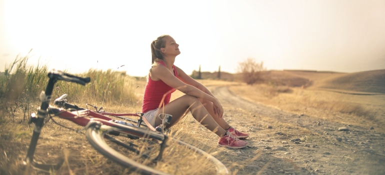 Picture of a woman sitting on a road next to a bike 